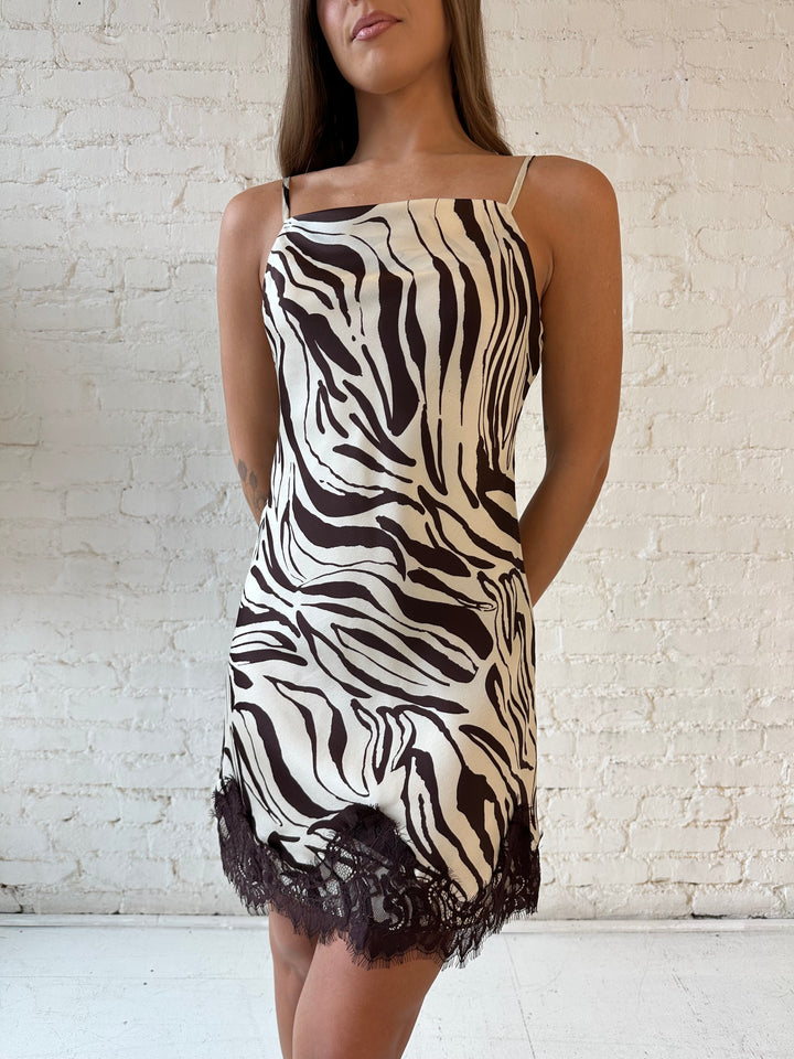 Woman wearing brown abstract pattern satin mini dress with dark brown lace trim. 