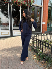 Woman wearing navy blue knit two piece set with button down cardigan and wide leg pant. 