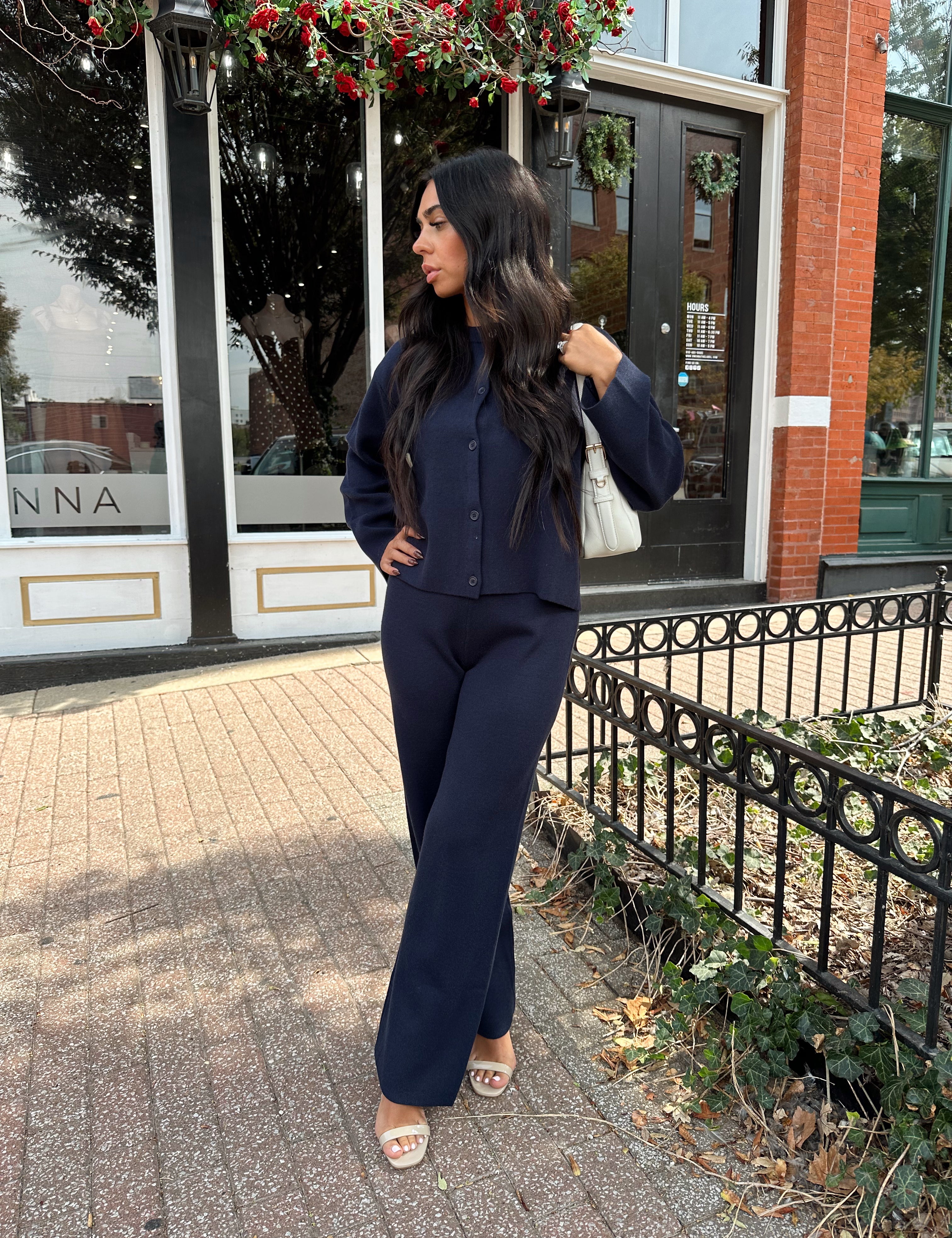Woman wearing navy blue knit two piece set with button down cardigan and wide leg pant. 