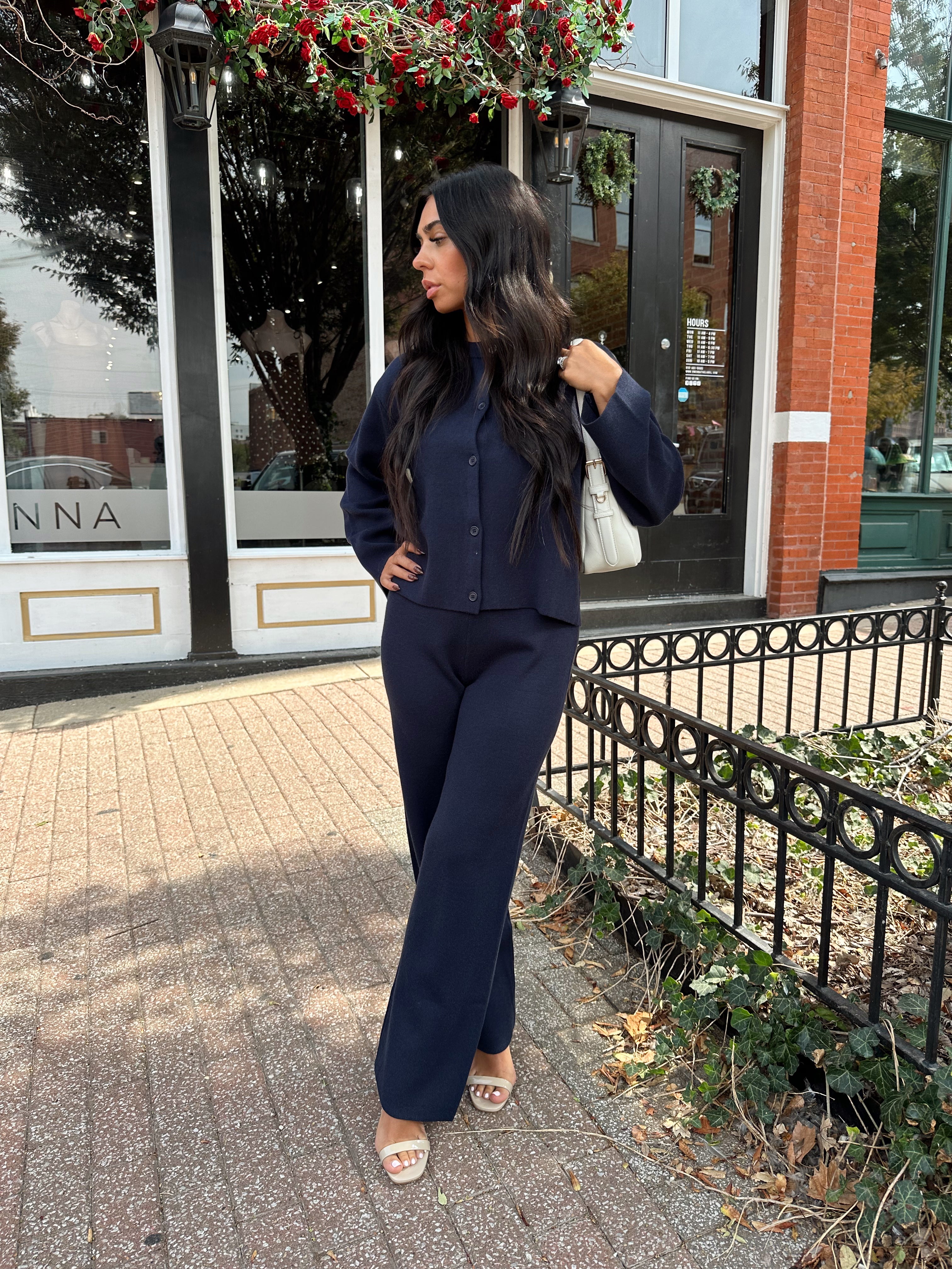 Woman wearing navy blue knit two piece set with button down cardigan and wide leg pant. 