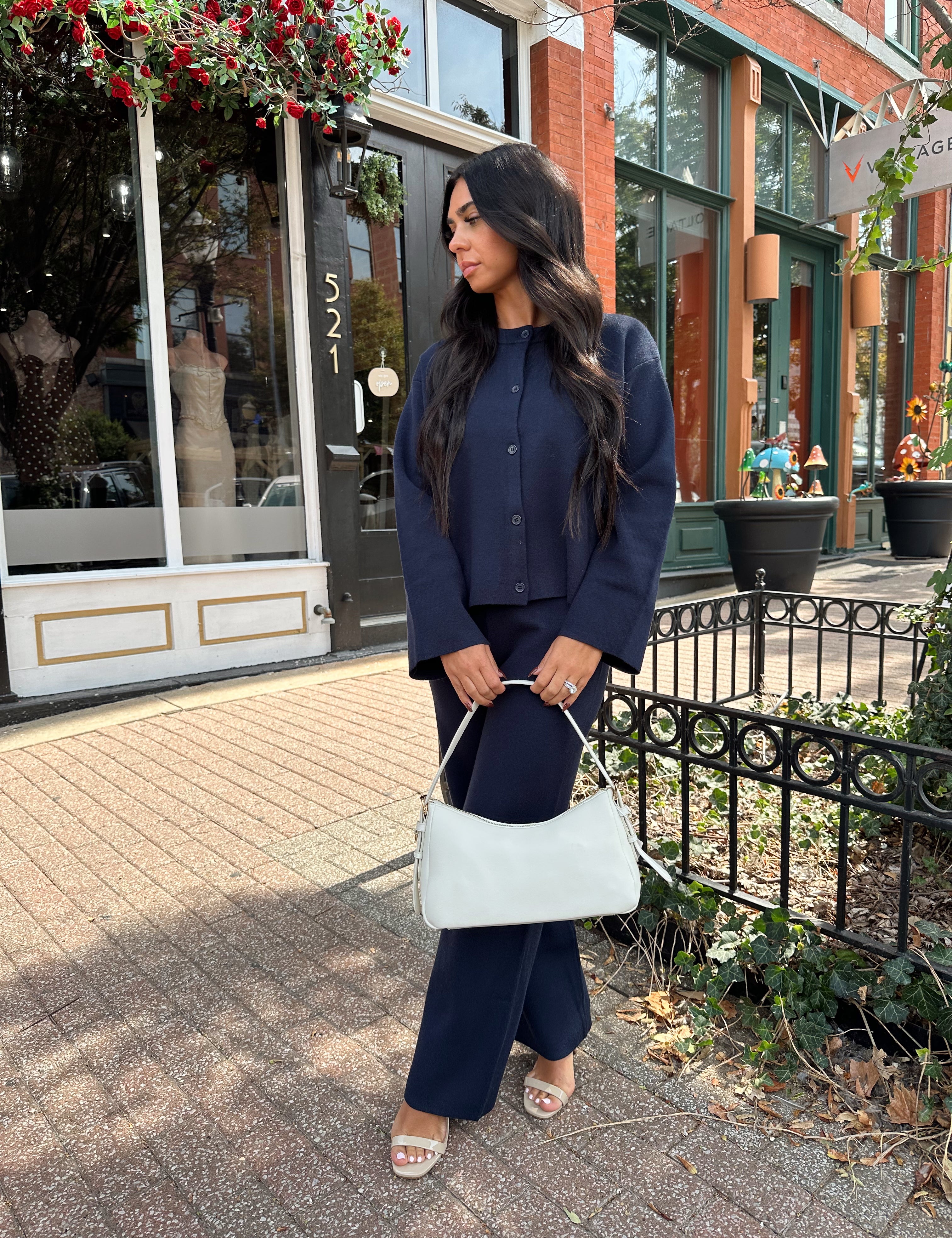 Woman wearing navy blue knit two piece set with button down cardigan and wide leg pant. 