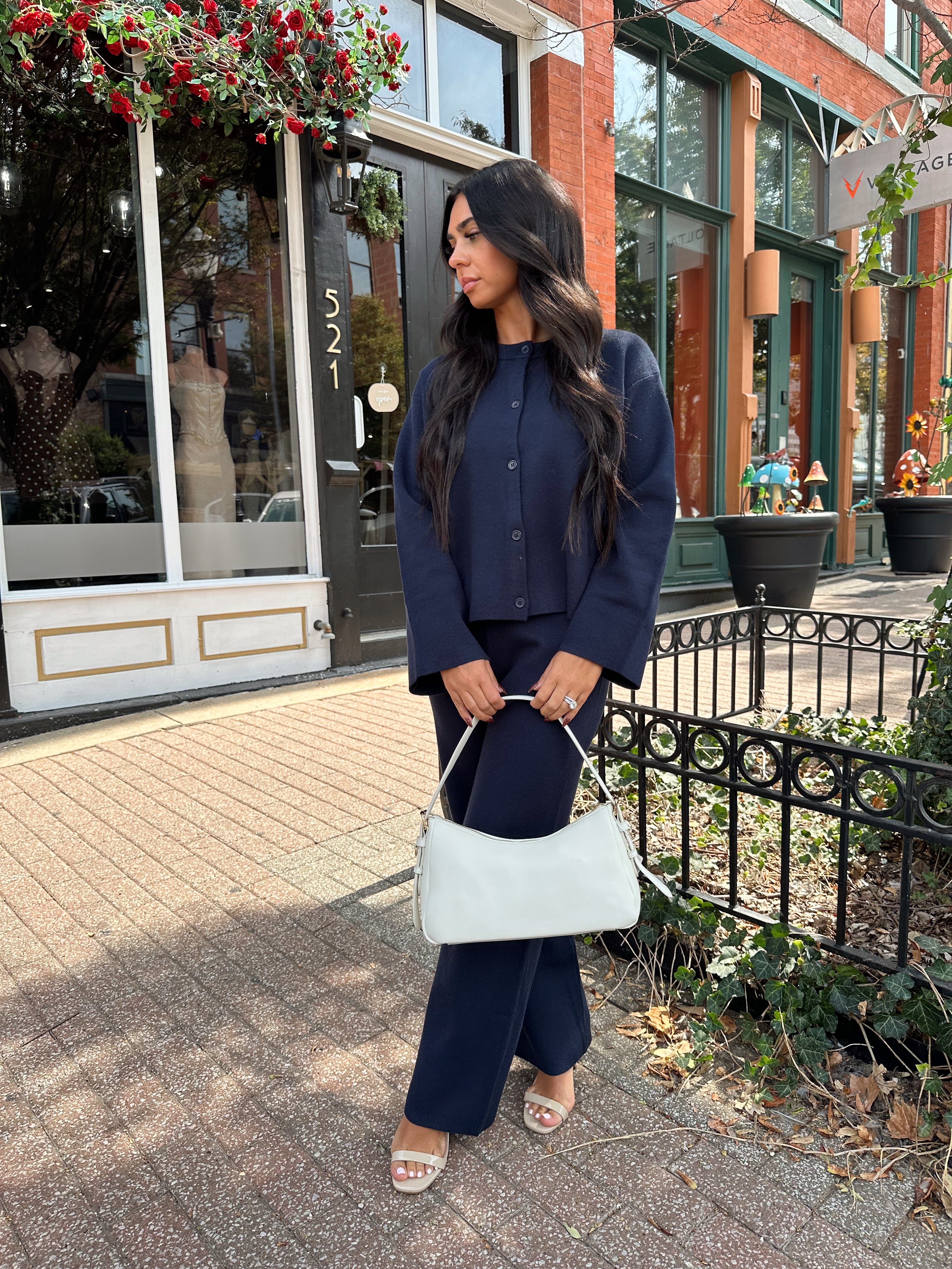 Woman wearing navy blue knit two piece set with button down cardigan and wide leg pant. 