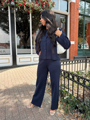 Woman wearing navy blue knit two piece set with button down cardigan and wide leg pant. 