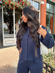 Woman wearing navy blue knit two piece set with button down cardigan and wide leg pant. 