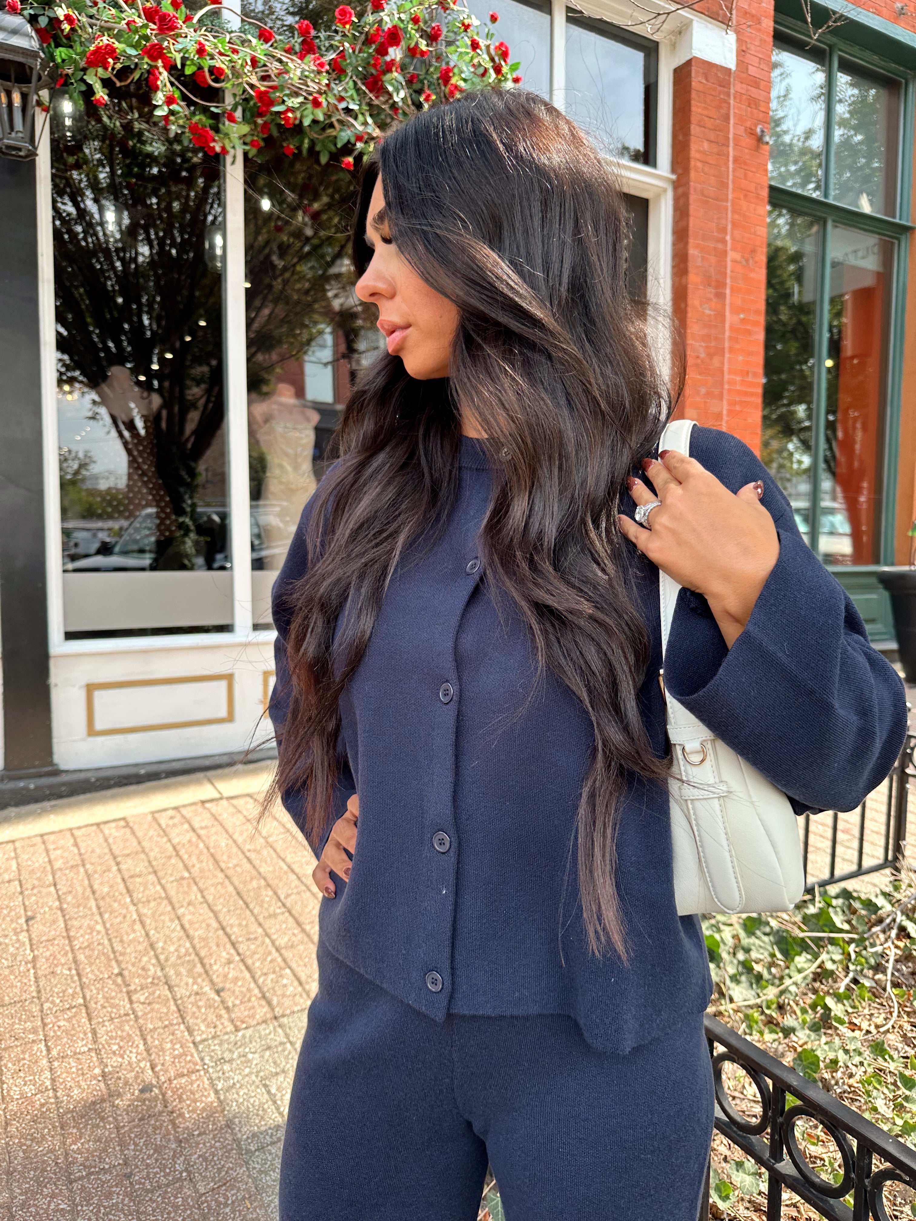Woman wearing navy blue knit two piece set with button down cardigan and wide leg pant. 