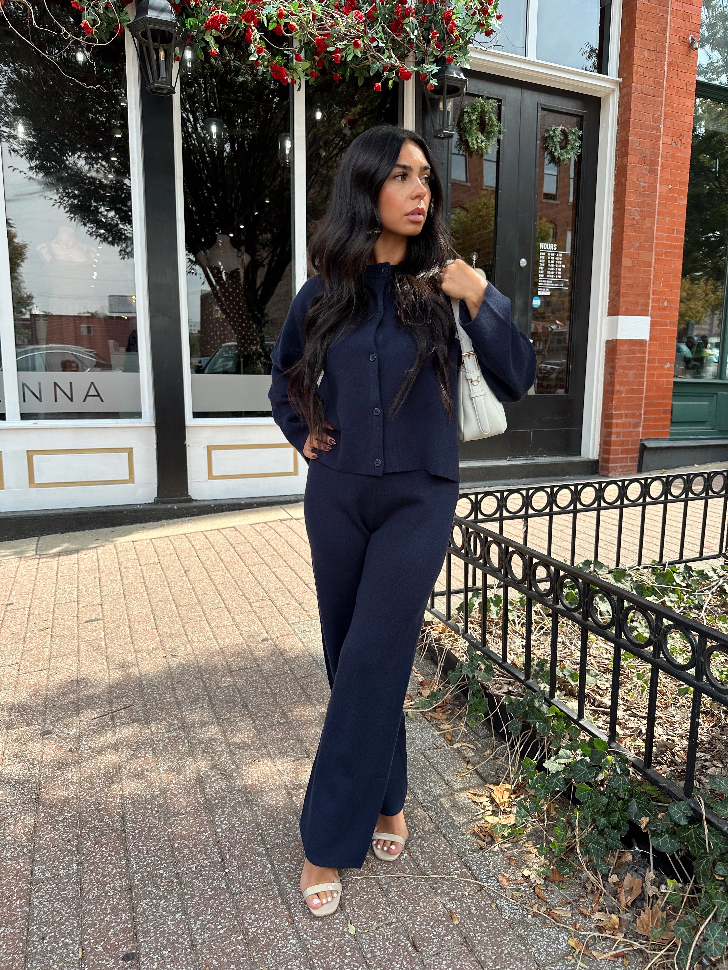 Woman wearing navy blue knit two piece set with button down cardigan and wide leg pant. 