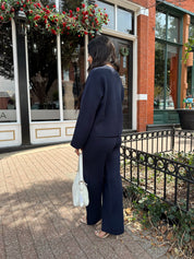 Woman wearing navy blue knit two piece set with button down cardigan and wide leg pant. 