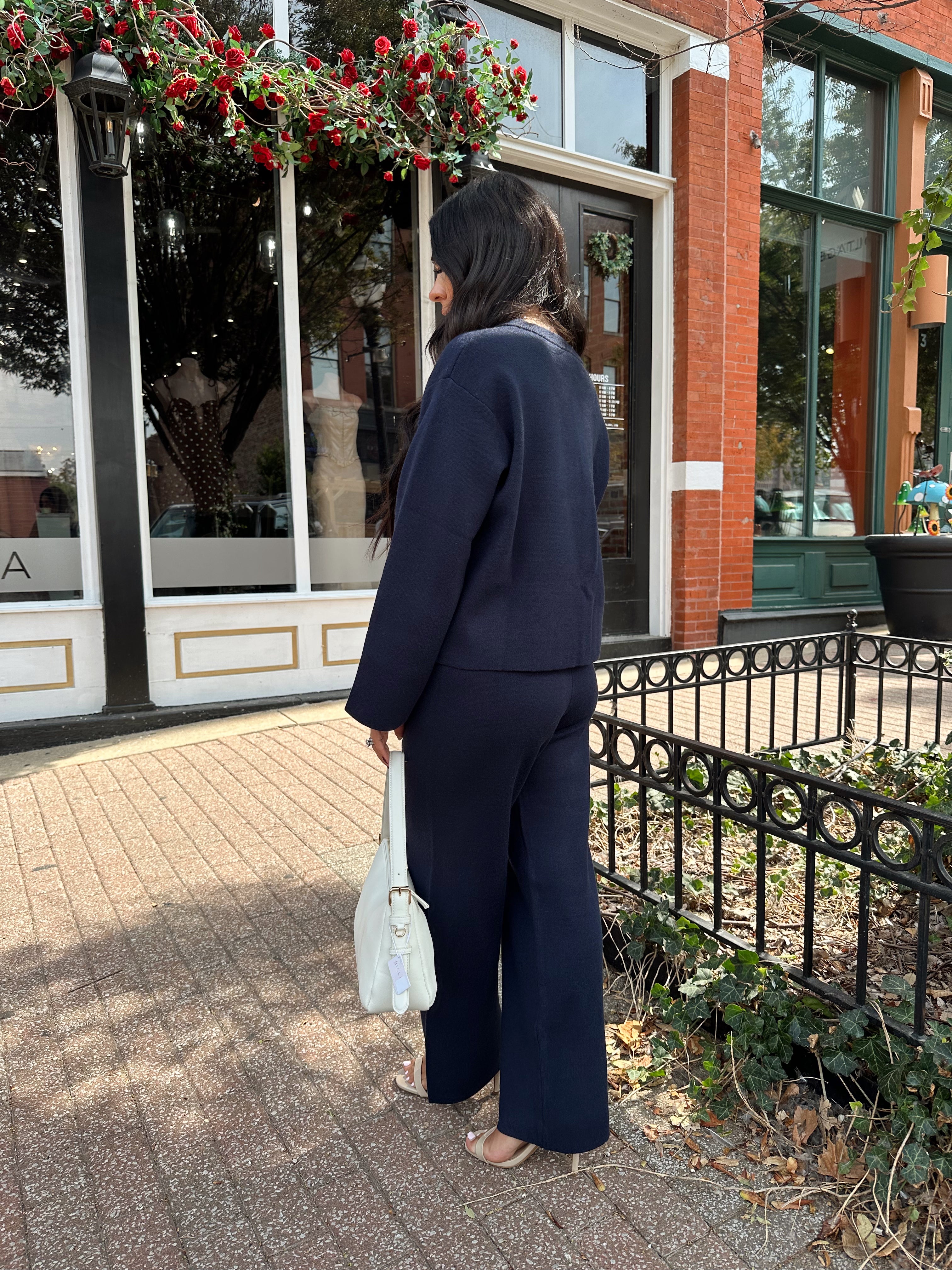 Woman wearing navy blue knit two piece set with button down cardigan and wide leg pant. 