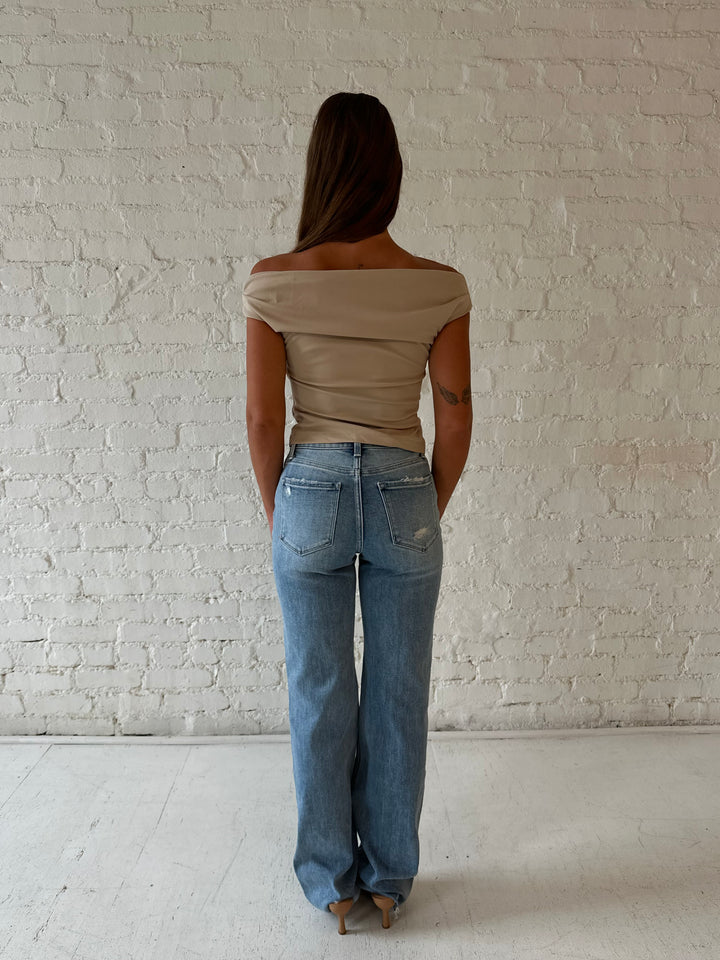 Woman wearing high waisted distressed jeans with brown tube top.