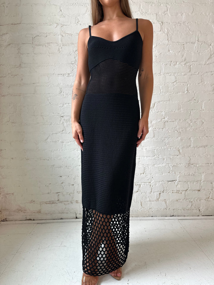 Woman wearing black knit maxi dress with netting bottom detail.