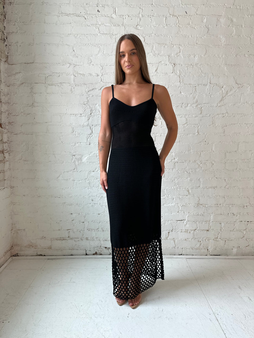 Woman wearing black knit maxi dress with netting bottom detail.