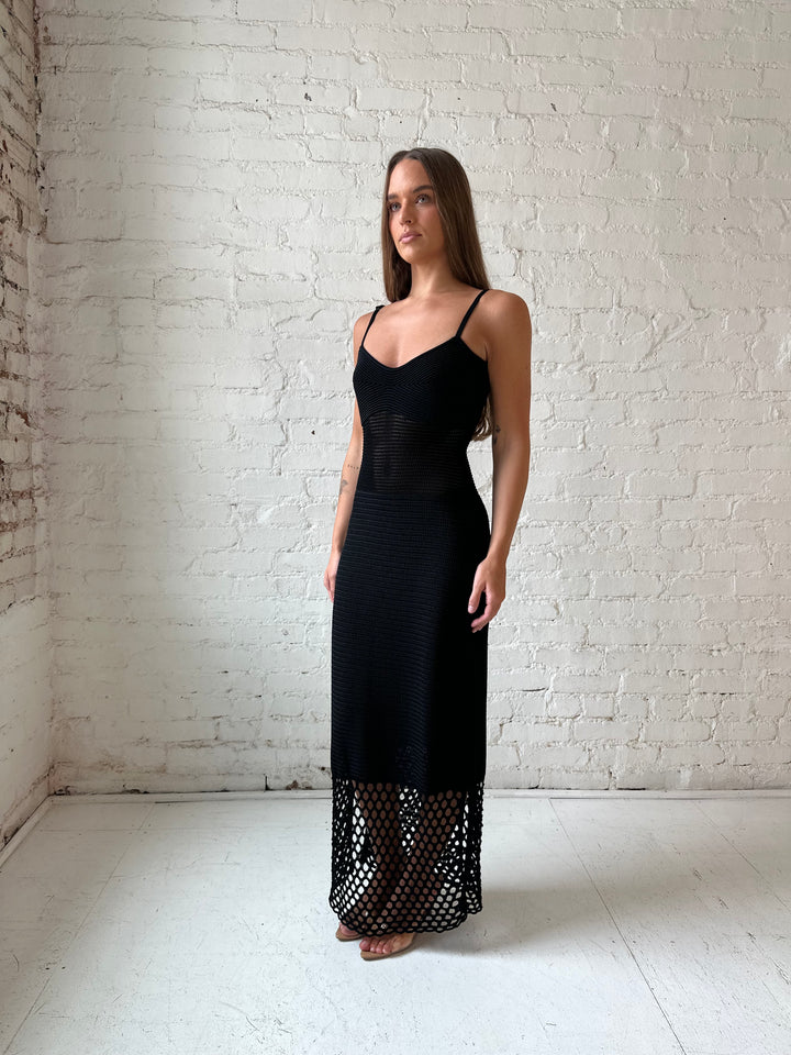 Woman wearing black knit maxi dress with netting bottom detail.