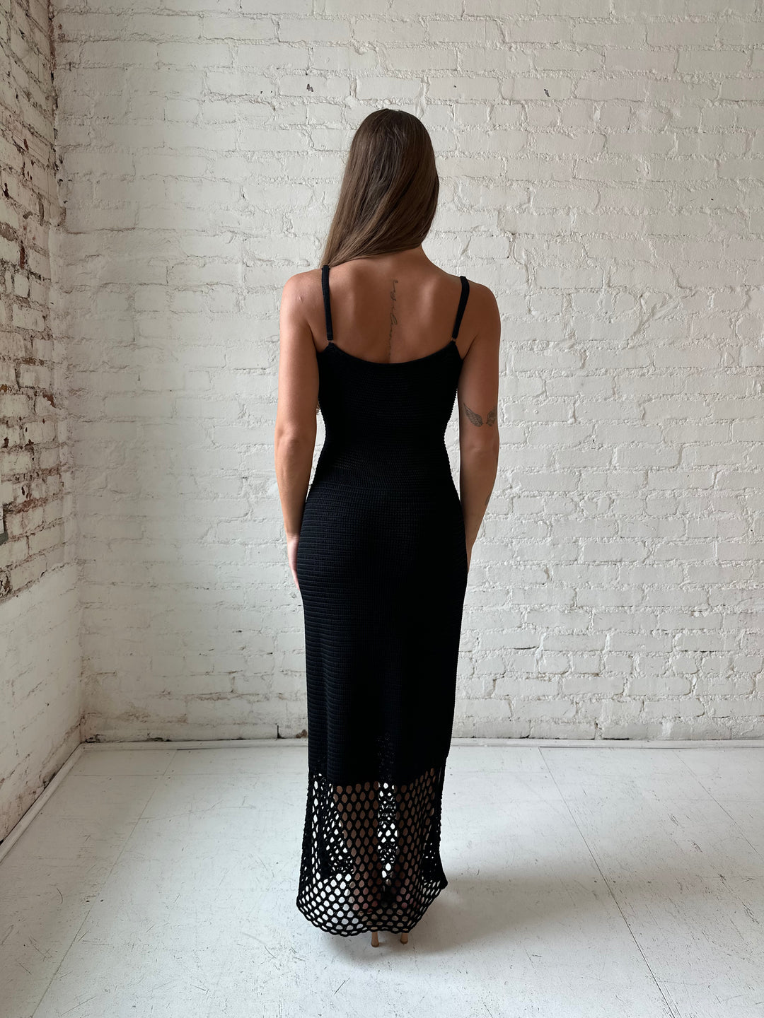 Woman wearing black knit maxi dress with netting bottom detail.