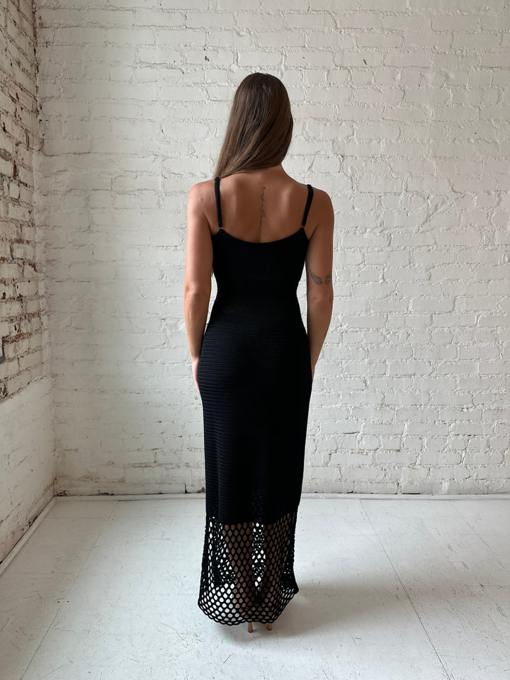 Woman wearing black knit maxi dress with netting bottom detail.