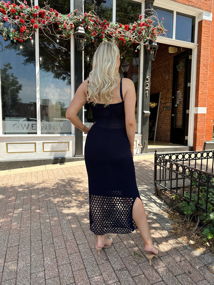 Woman wearing navy blue knit midi dress with netting bottom and adjustable straps. 