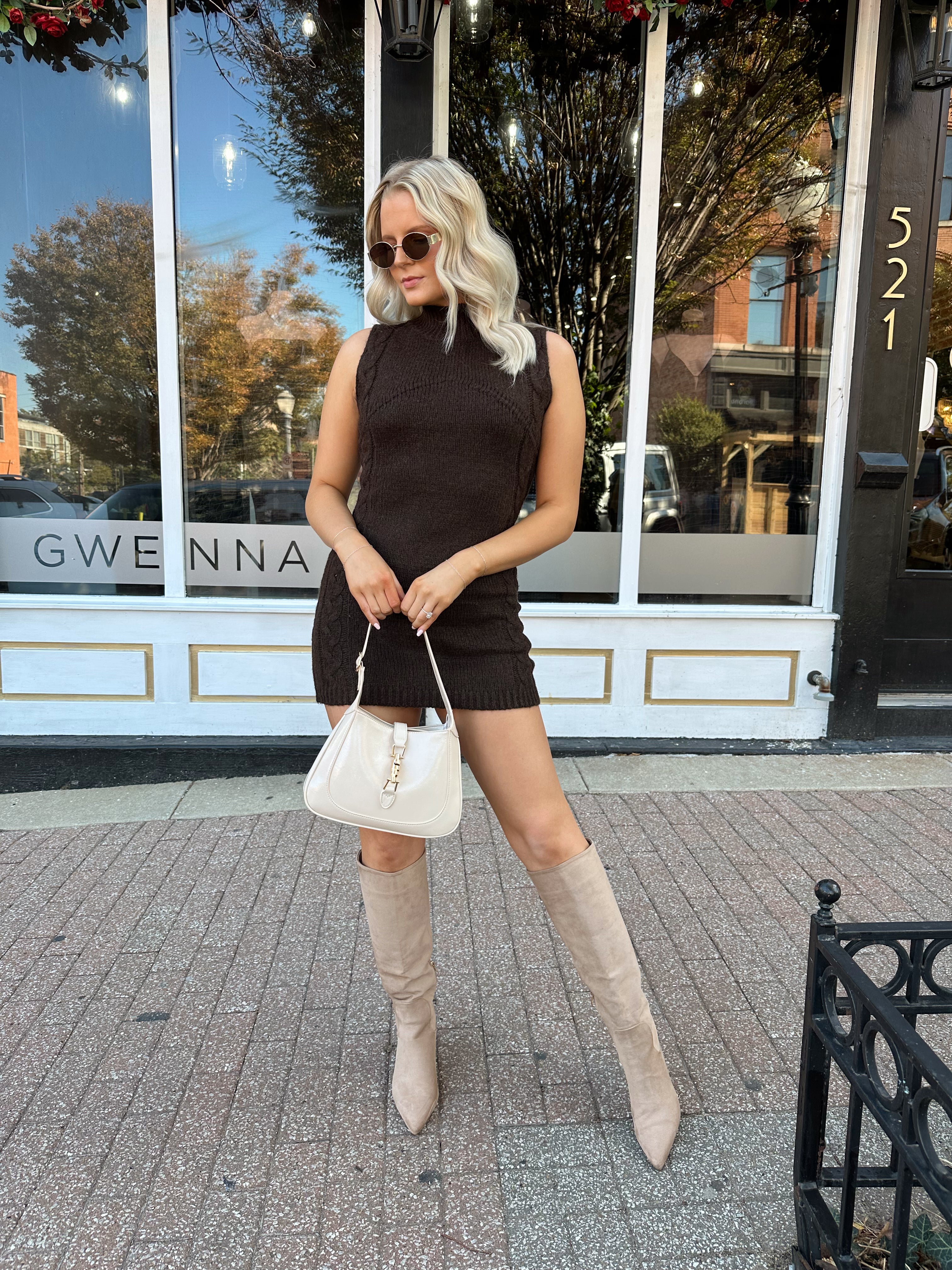 Woman wearing dark brown sleeveless sweater dress with suede knee boot.
