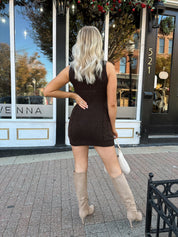 Woman wearing dark brown sleeveless sweater dress with suede knee boot.