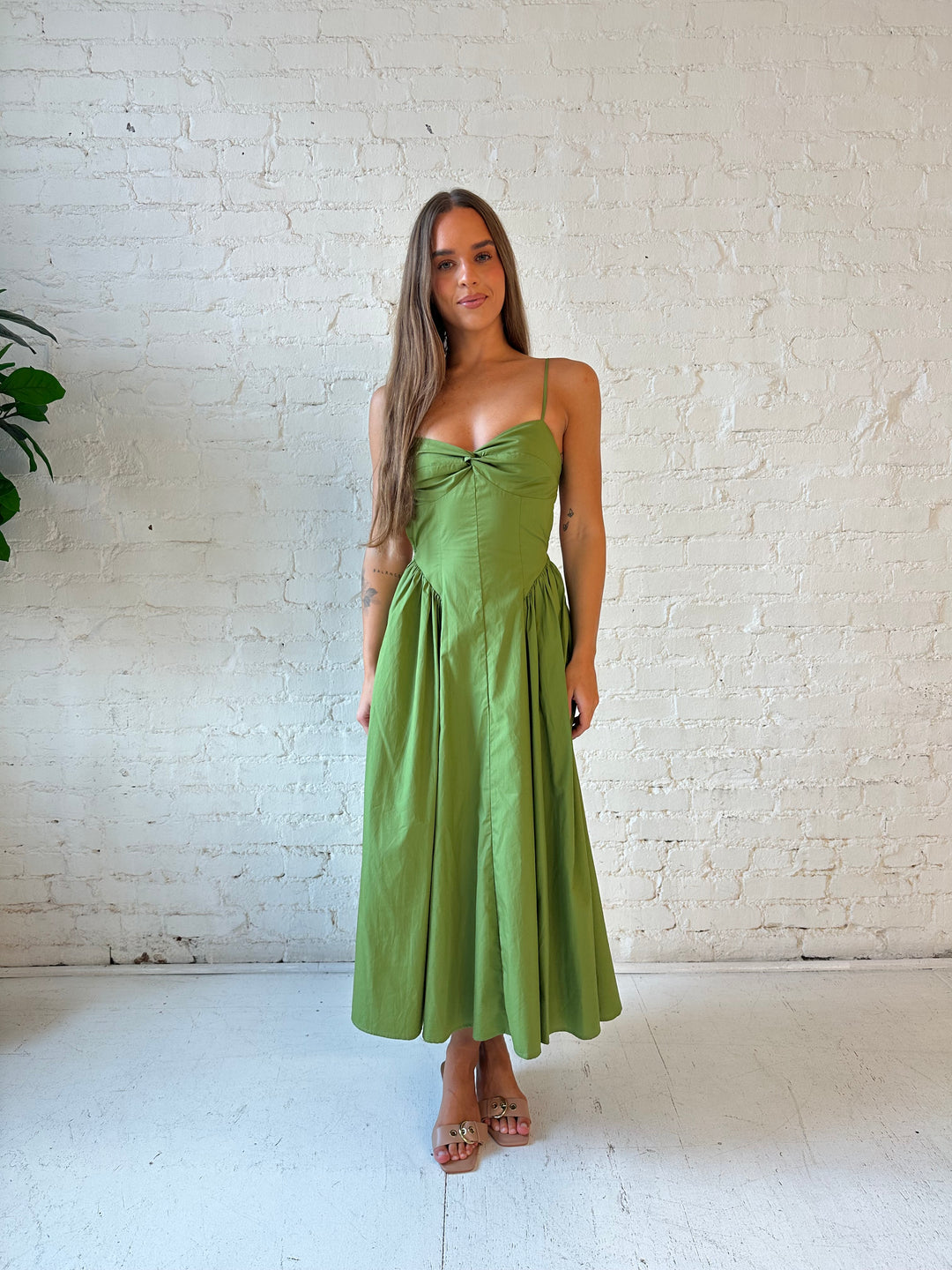 Woman wearing olive green drop waist midi dress with an open back. 