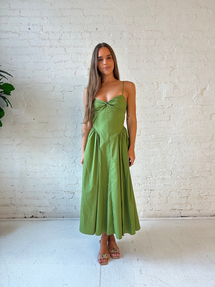 Woman wearing olive green drop waist midi dress with an open back. 