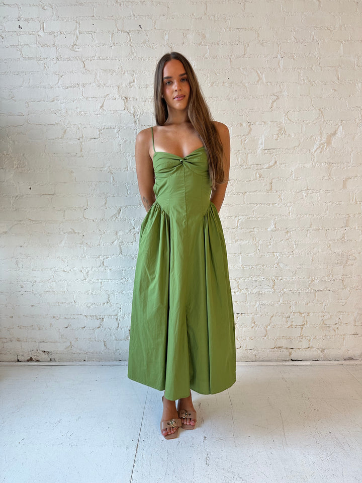 Woman wearing olive green drop waist midi dress with an open back. 