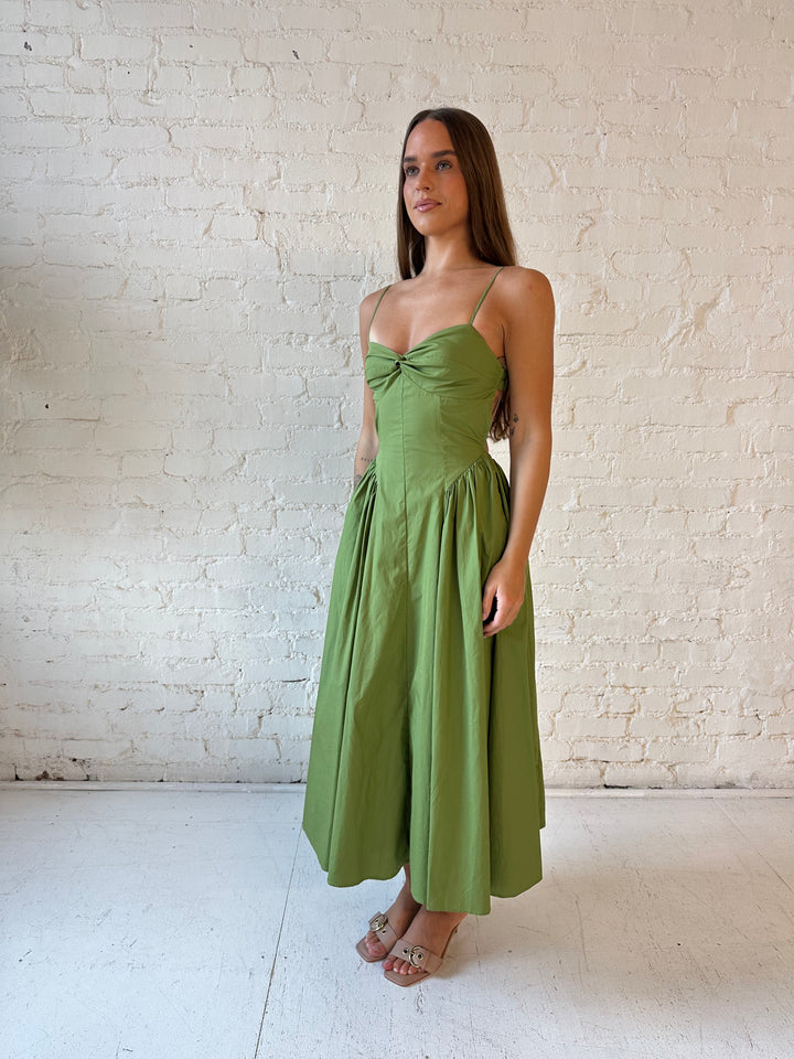 Woman wearing olive green drop waist midi dress with an open back. 