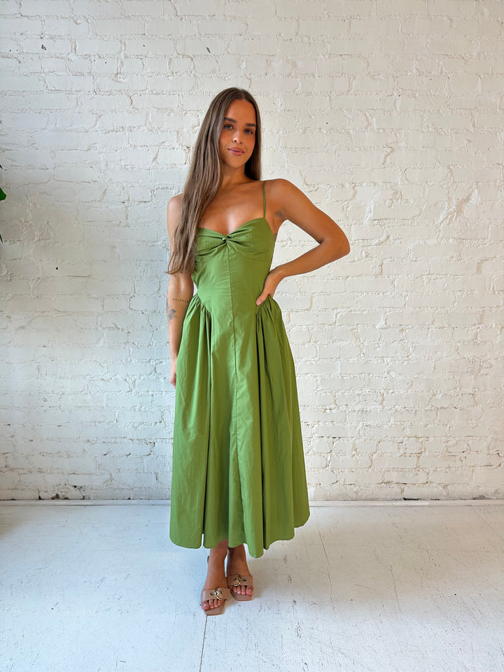 Woman wearing olive green drop waist midi dress with an open back. 