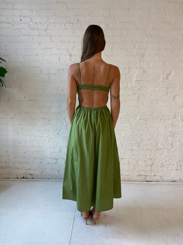 Woman wearing olive green drop waist midi dress with an open back. 