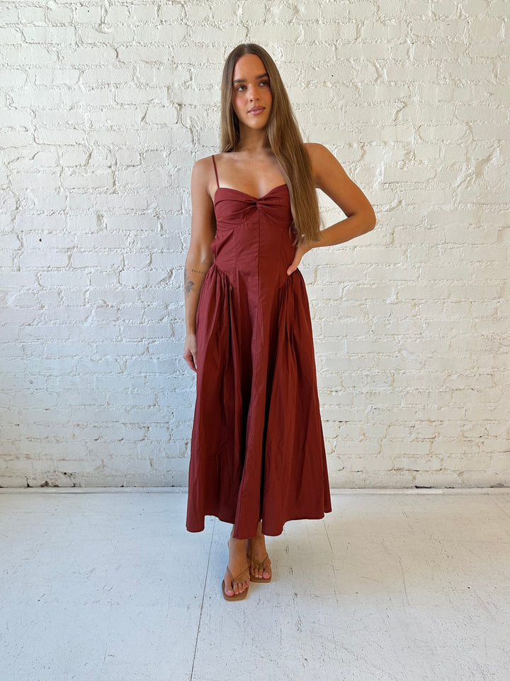Woman wearing rust colored drop waist midi dress with sweetheart neckline, and open back.
