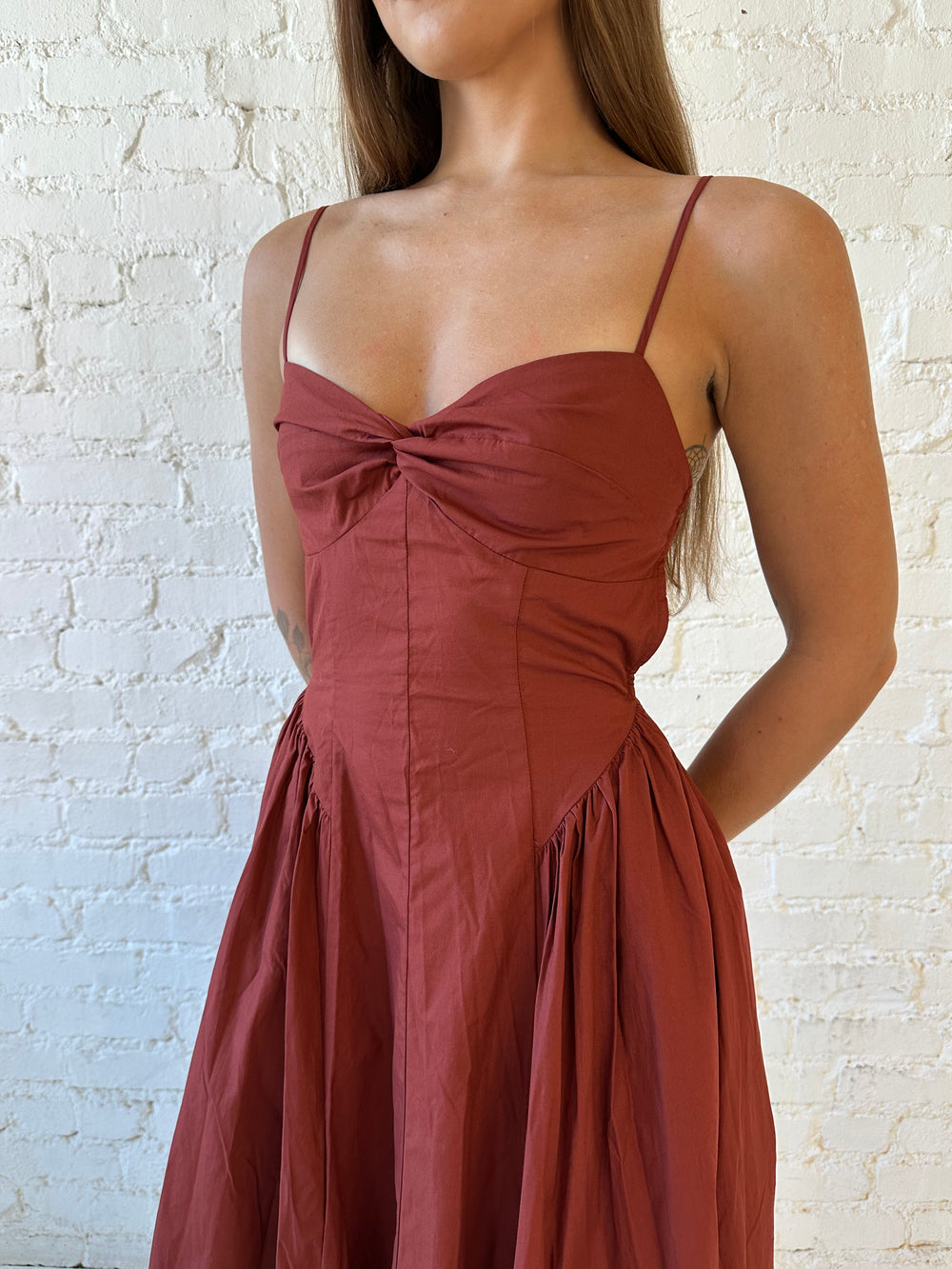 Woman wearing rust colored drop waist midi dress with sweetheart neckline, and open back.