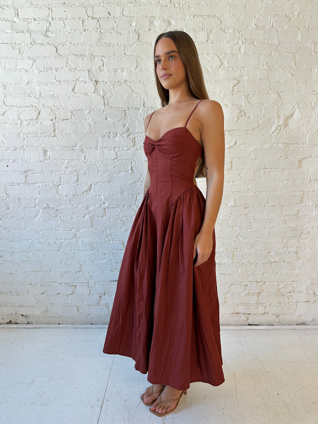 Woman wearing rust colored drop waist midi dress with sweetheart neckline, and open back.