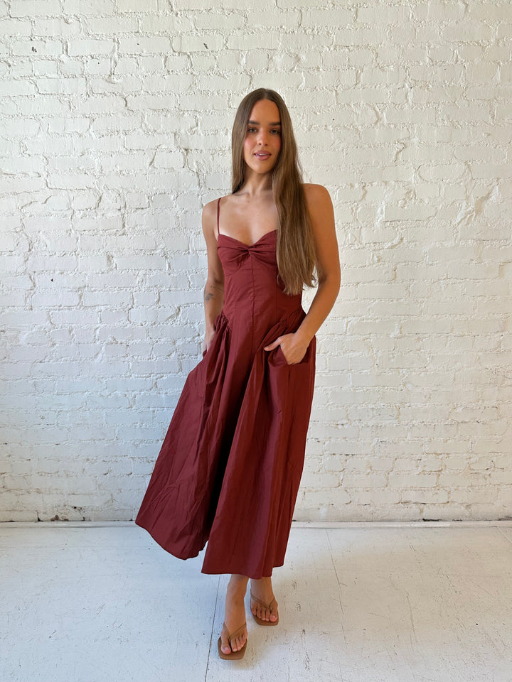 Woman wearing rust colored drop waist midi dress with sweetheart neckline, and open back.