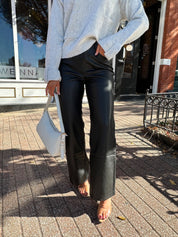 Woman wearing black leather high waisted pant with grey knit sweater. 
