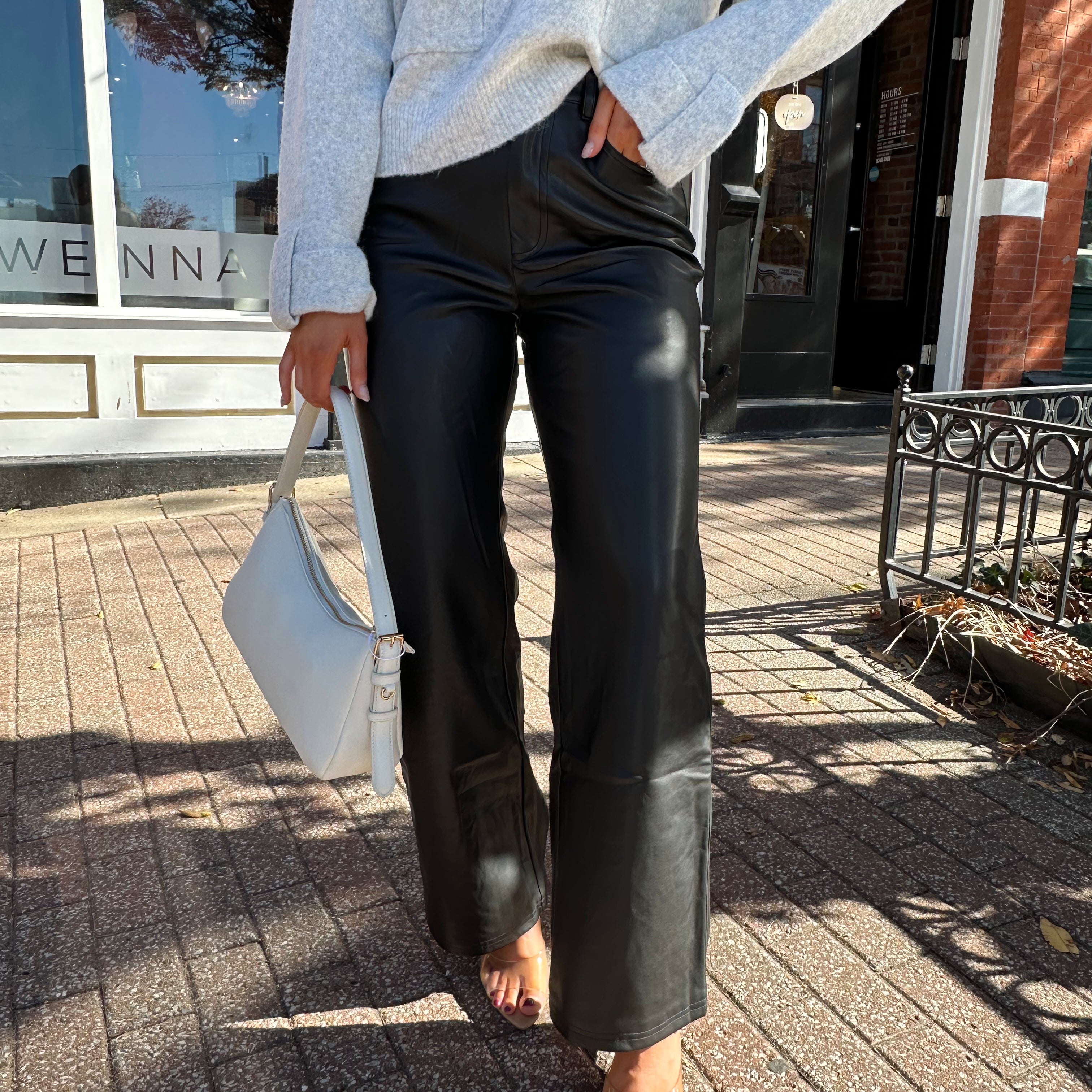 Woman wearing black leather high waisted pant with grey knit sweater. 