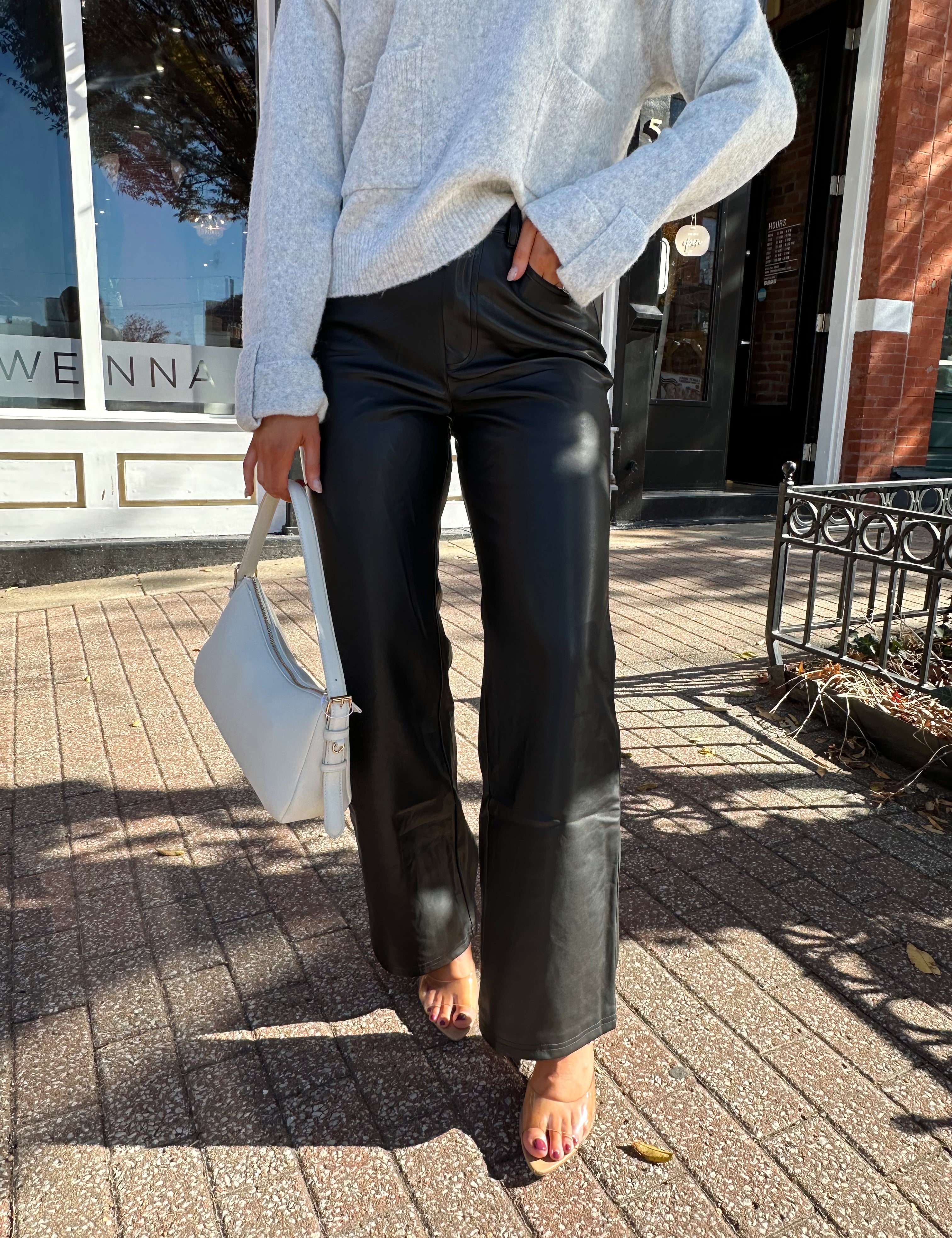 Woman wearing black leather high waisted pant with grey knit sweater. 