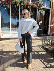 Woman wearing black leather high waisted pant with grey knit sweater. 