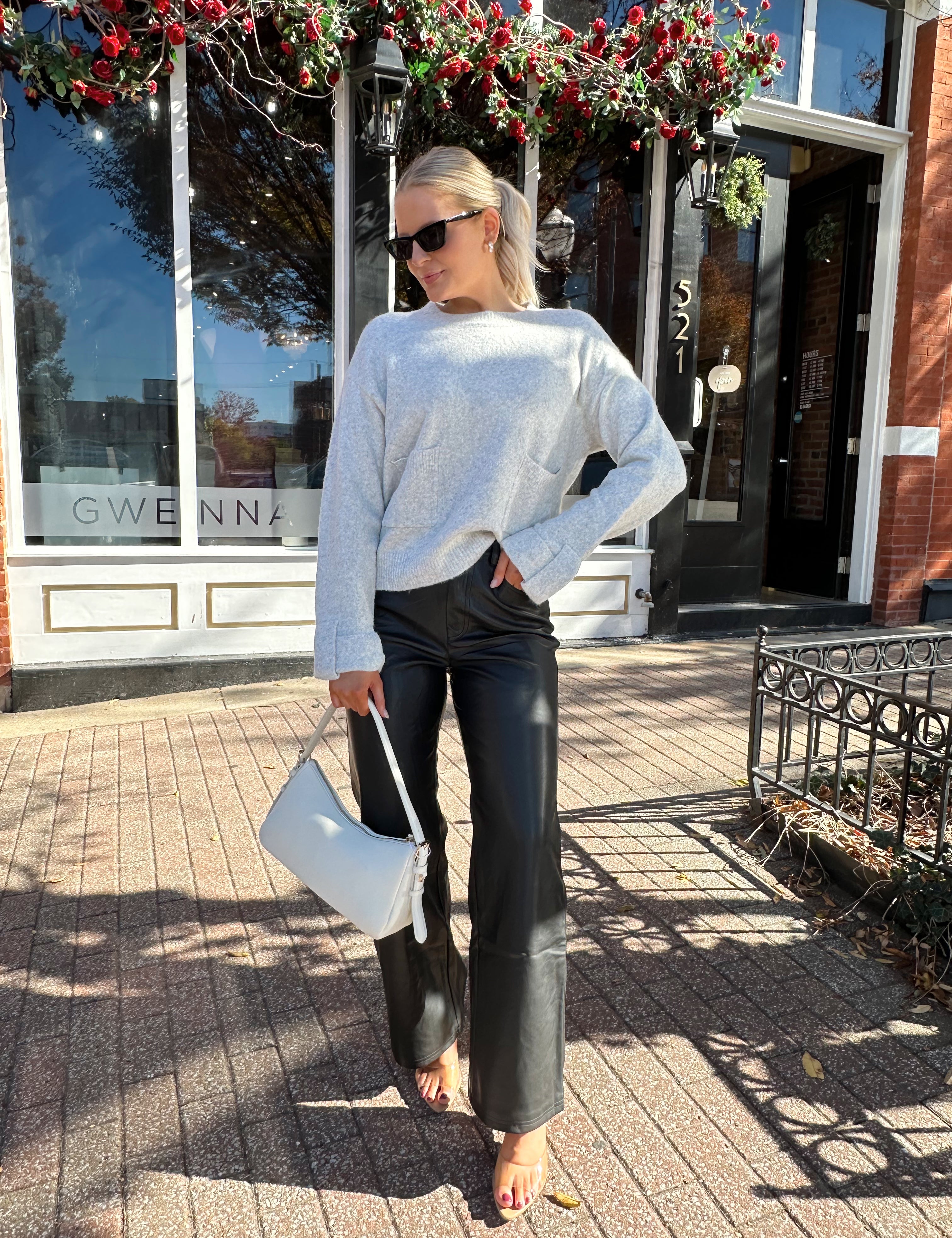 Woman wearing black leather high waisted pant with grey knit sweater. 