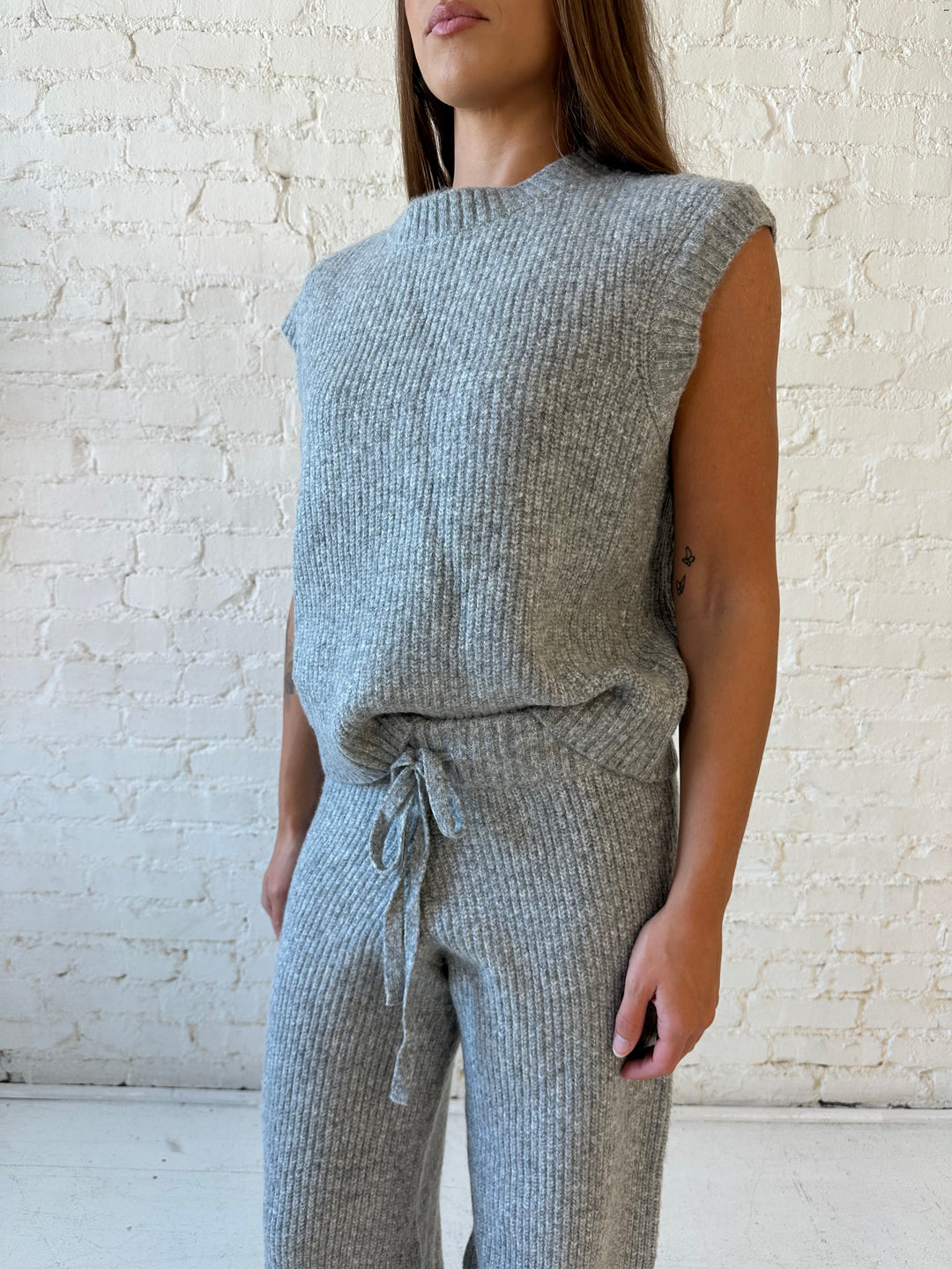 Woman wearing grey knit sweater two piece lounge set with short sleeve top, and wide leg pant. 