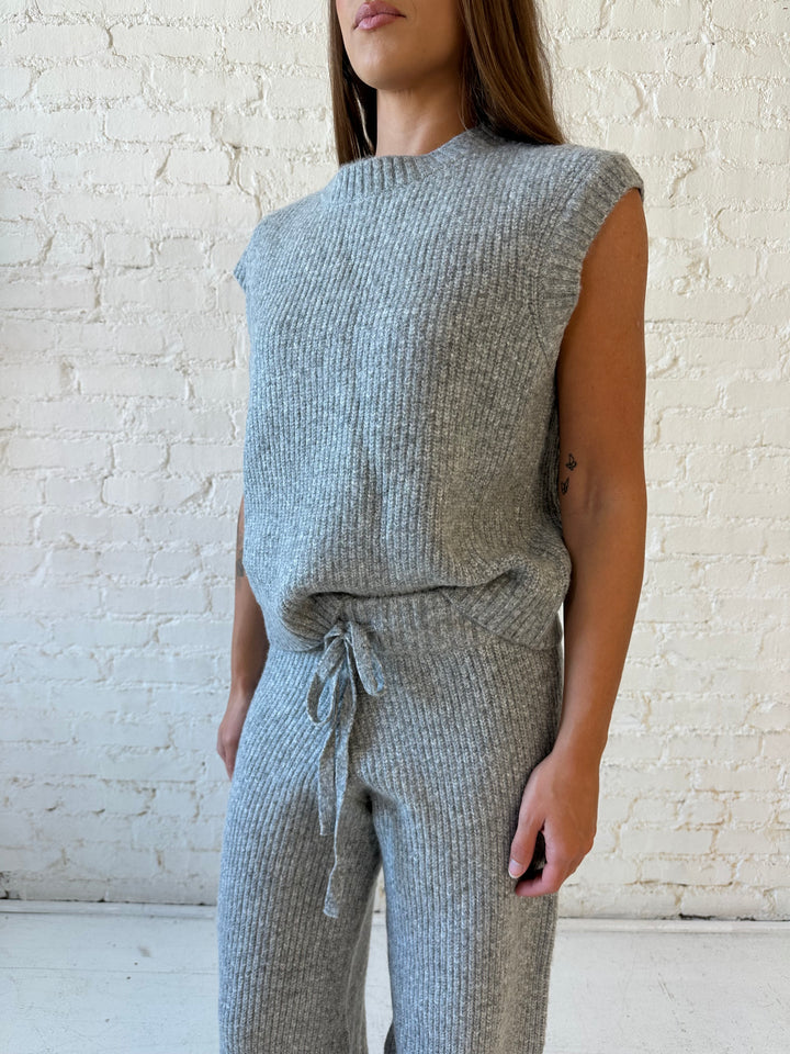 Woman wearing grey knit sweater two piece lounge set with short sleeve top, and wide leg pant. 