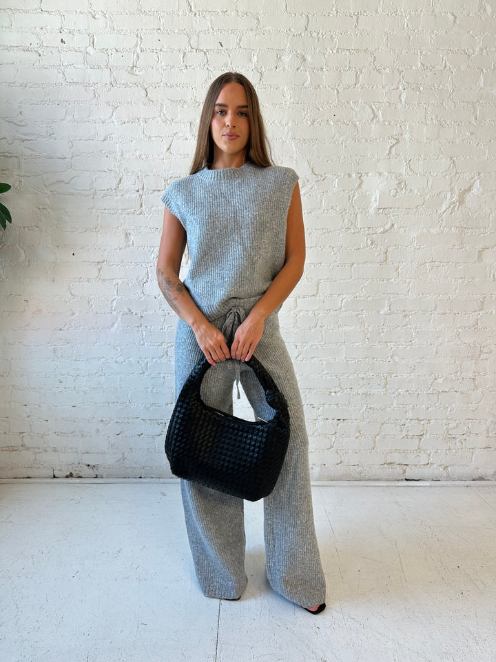 Woman wearing grey knit sweater two piece lounge set with short sleeve top, and wide leg pant. 