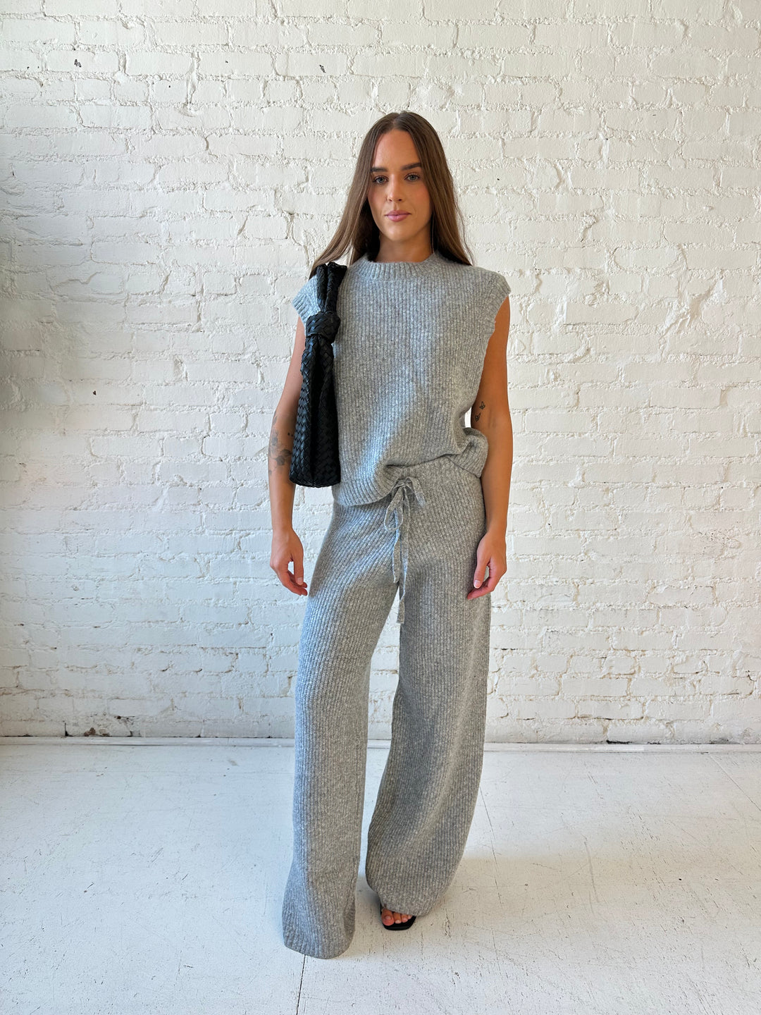 Woman wearing grey knit sweater two piece lounge set with short sleeve top, and wide leg pant. 