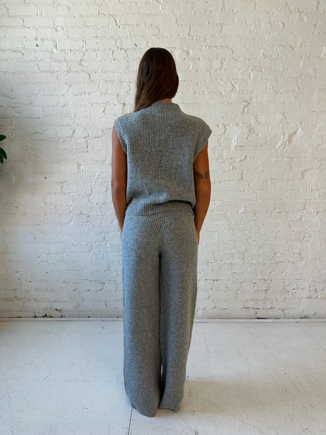 Woman wearing grey knit sweater two piece lounge set with short sleeve top, and wide leg pant. 