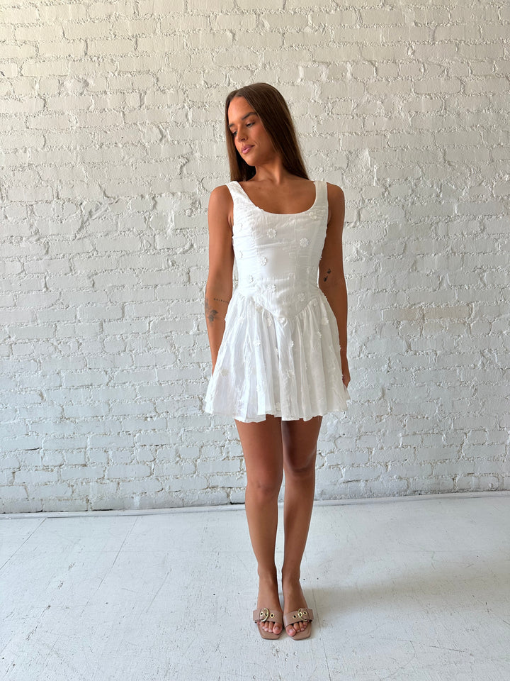 Woman wearing white fit to flare mini dress with embroidered floral detail. 