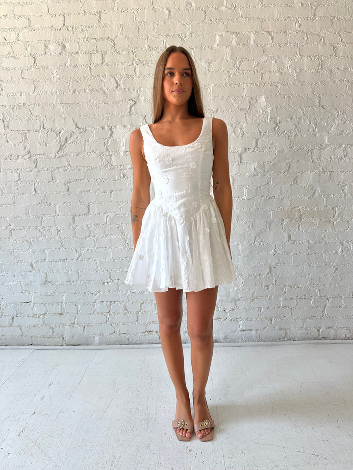 Woman wearing white fit to flare mini dress with embroidered floral detail. 