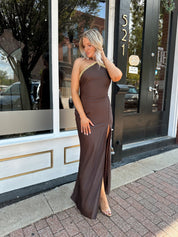 Woman wearing a dark brown satin maxi halter maxi dress with gold trim.