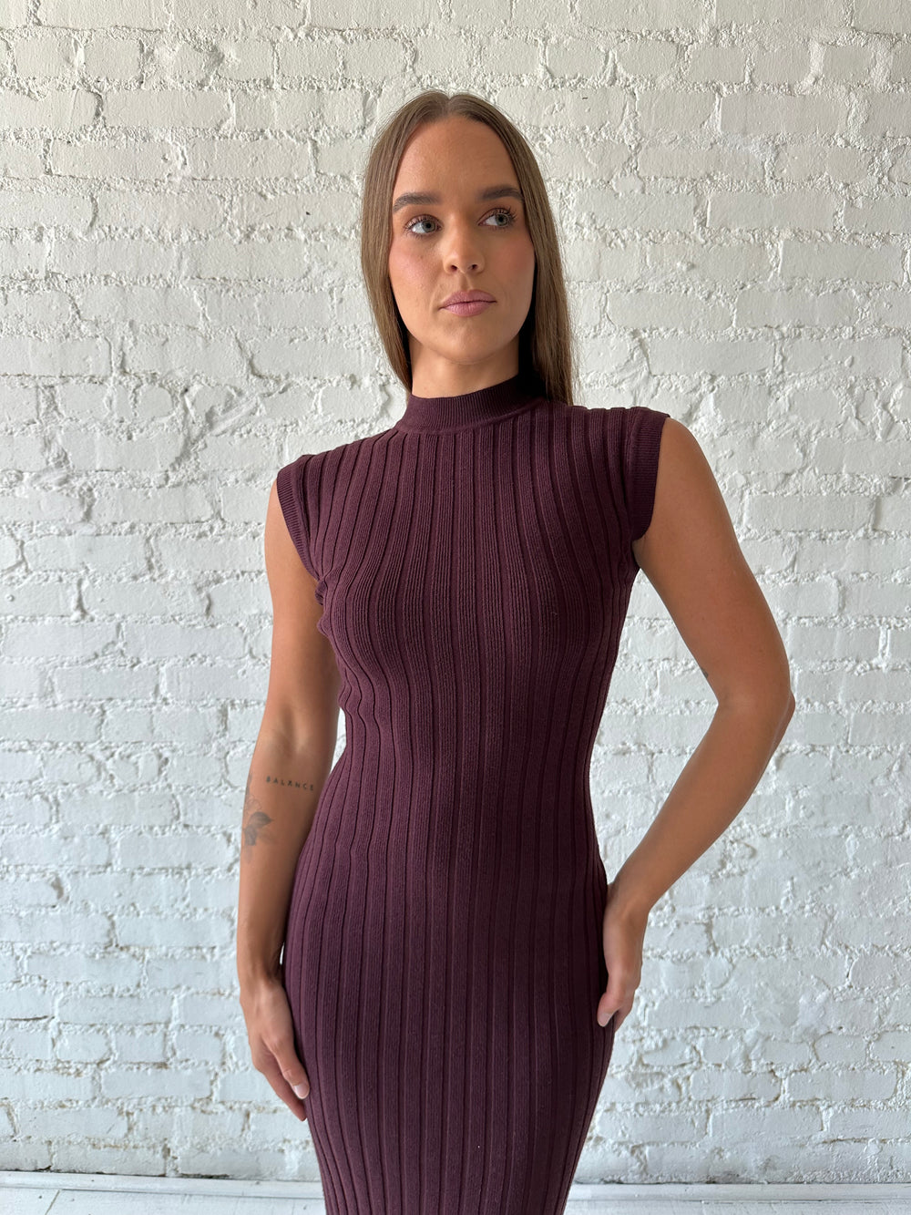Woman wearing a burgundy knit midi dress with high neckline.
