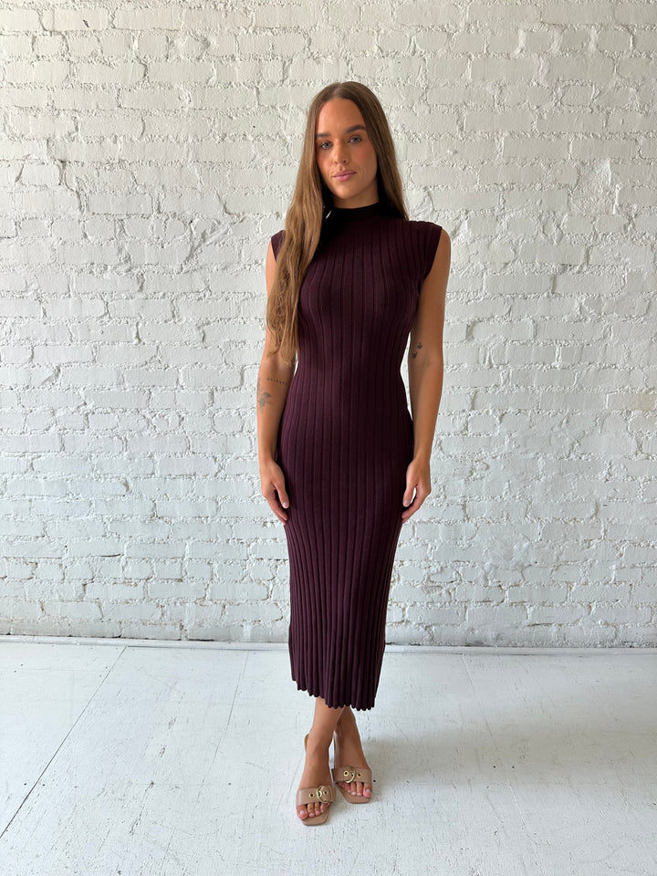Woman wearing a burgundy knit midi dress with high neckline.