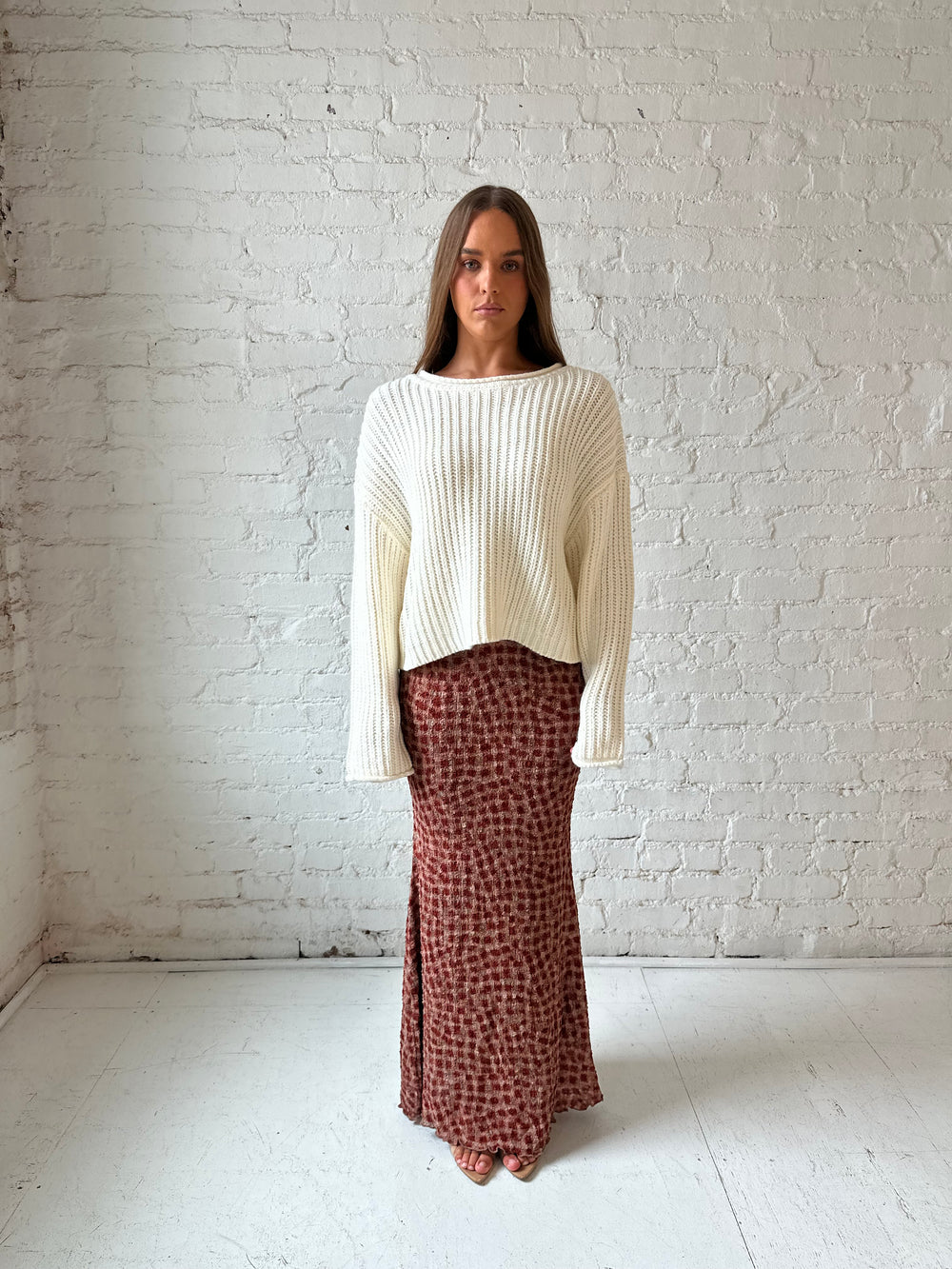 Woman wearing cream knit sweater with burgundy textured dotted maxi skirt.