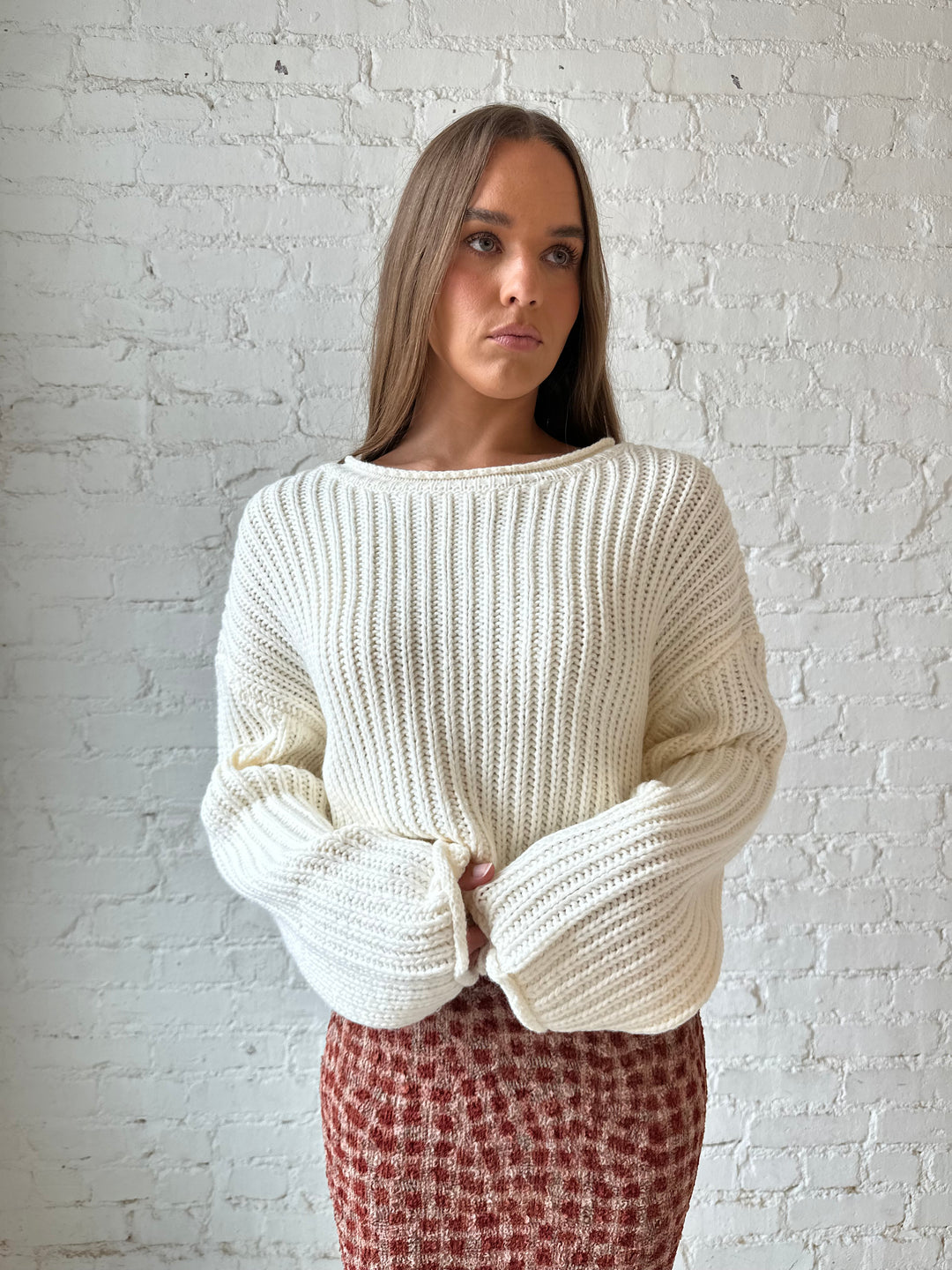 Woman wearing cream knit sweater with burgundy textured dotted maxi skirt.