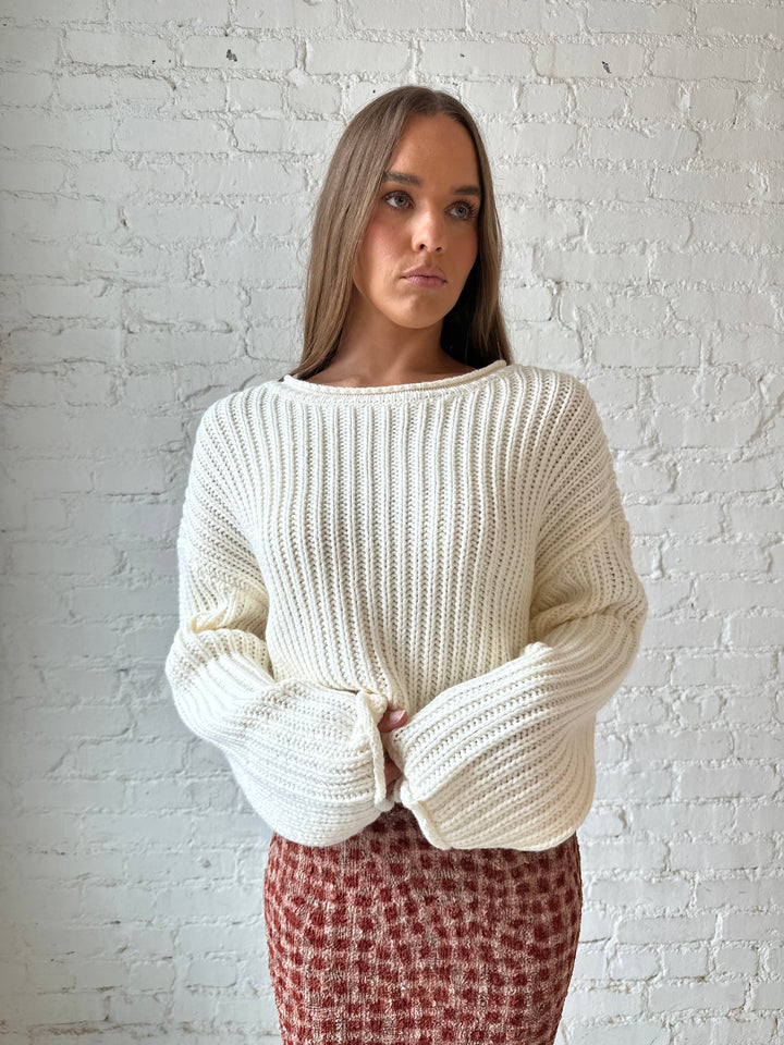 Woman wearing cream knit sweater with burgundy textured dotted maxi skirt.