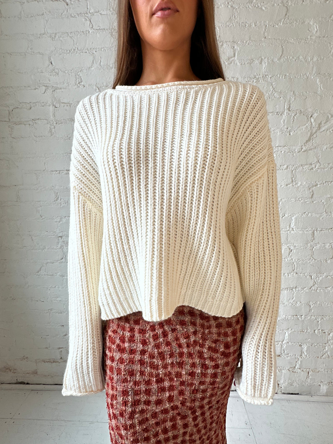 Woman wearing cream knit sweater with burgundy textured dotted maxi skirt.
